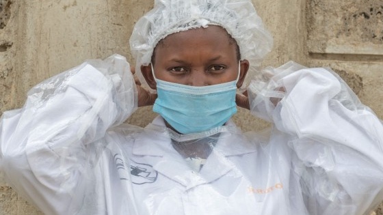 A SilAfrica team member wearing a PPE gown and putting on face mask